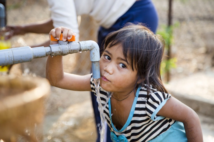 Kind trinkt Wasser aus einem Wasserhahn